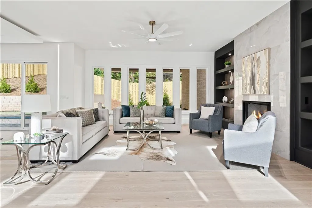 Living room featuring built in shelves, a healthy amount of sunlight, and light hardwood / wood-style floors Living room featuring built in shelves, a healthy amount of sunlight, and light hardwood / wood-style floors