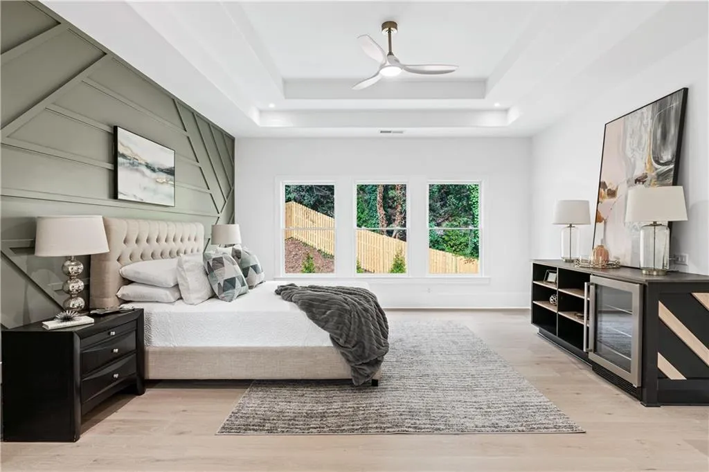 Bedroom with a tray ceiling, ceiling fan, and light wood-type flooring Bedroom with a tray ceiling, ceiling fan, and light wood-type flooring