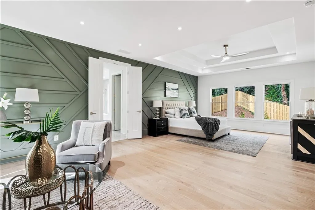 Bedroom featuring ceiling fan, a raised ceiling, and light hardwood / wood-style flooring Bedroom featuring ceiling fan, a raised ceiling, and light hardwood / wood-style flooring