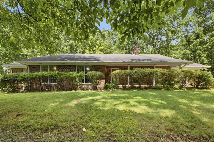 Brick exterior with a covered porch, mature landscaping, and a natural grass lawn