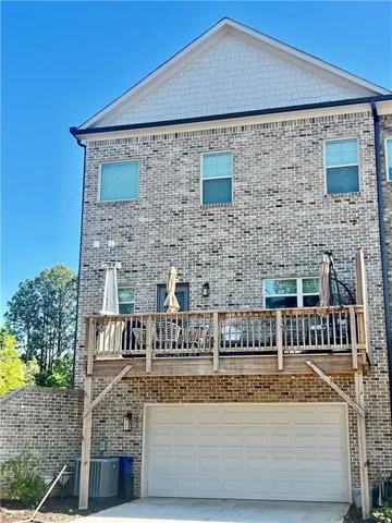 Brick exterior with a gabled roofline, second-story balcony, and an integrated garage