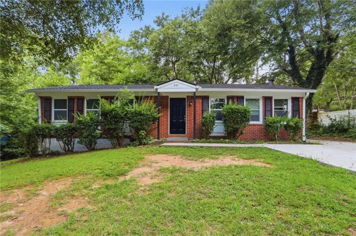 Brick facade home featuring a contrasting dark entry door, white trim, and a black shingle roof