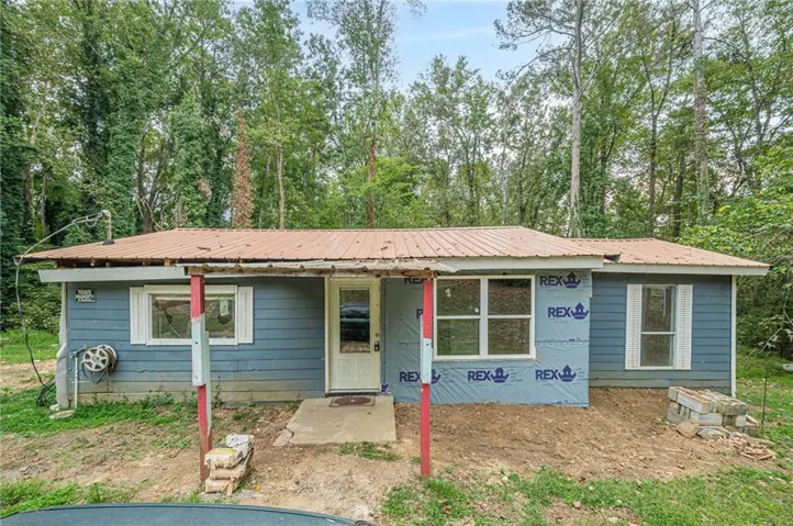 View of front of house featuring a metal roof, a porch, and view of wooded area