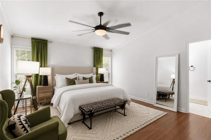 Vaulted ceiling bedroom featuring wood-finish flooring, a ceiling fan with integrated lighting, and crown molding