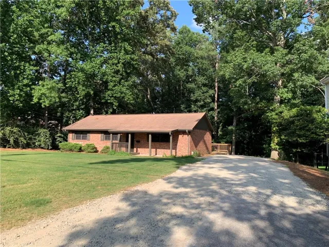 Lakefront Lanier... DIRECT lake access with unique "Permitted Garage" right on the shoreline. 4 Sides Brick ranch-style home featuring an expansive gravel driveway, a covered front porch, great front yard.