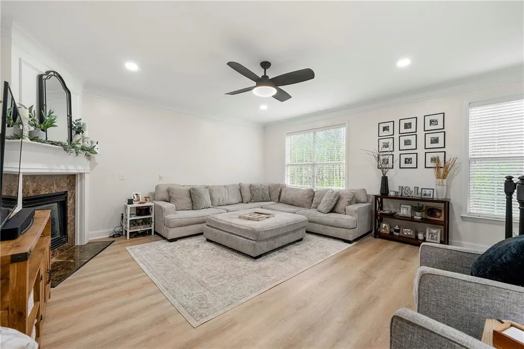 Living room featuring ornamental molding, ceiling fan, light hardwood / wood-style floors, and a high end fireplace