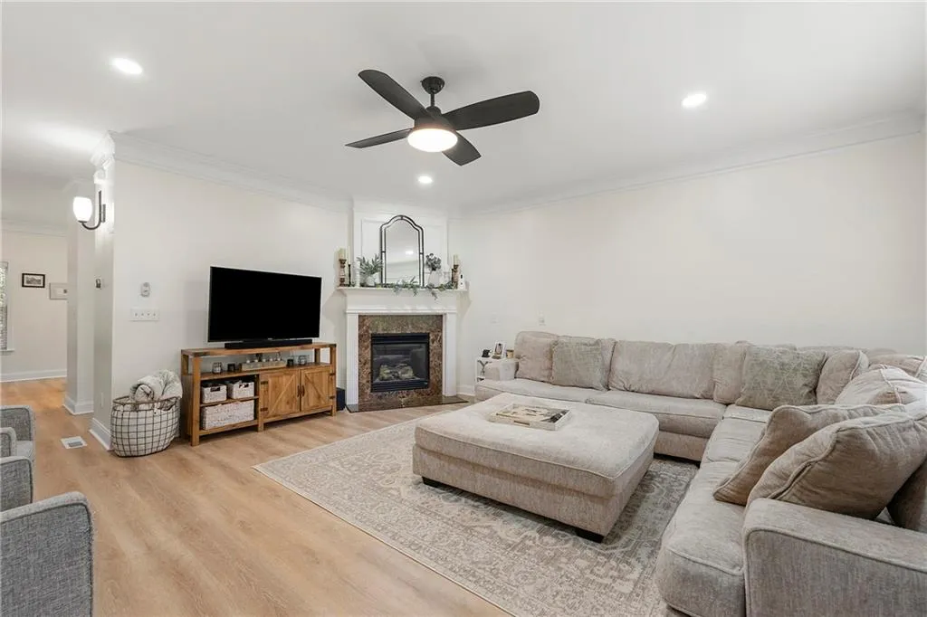 Living room with ceiling fan, crown molding, and light wood-type flooring