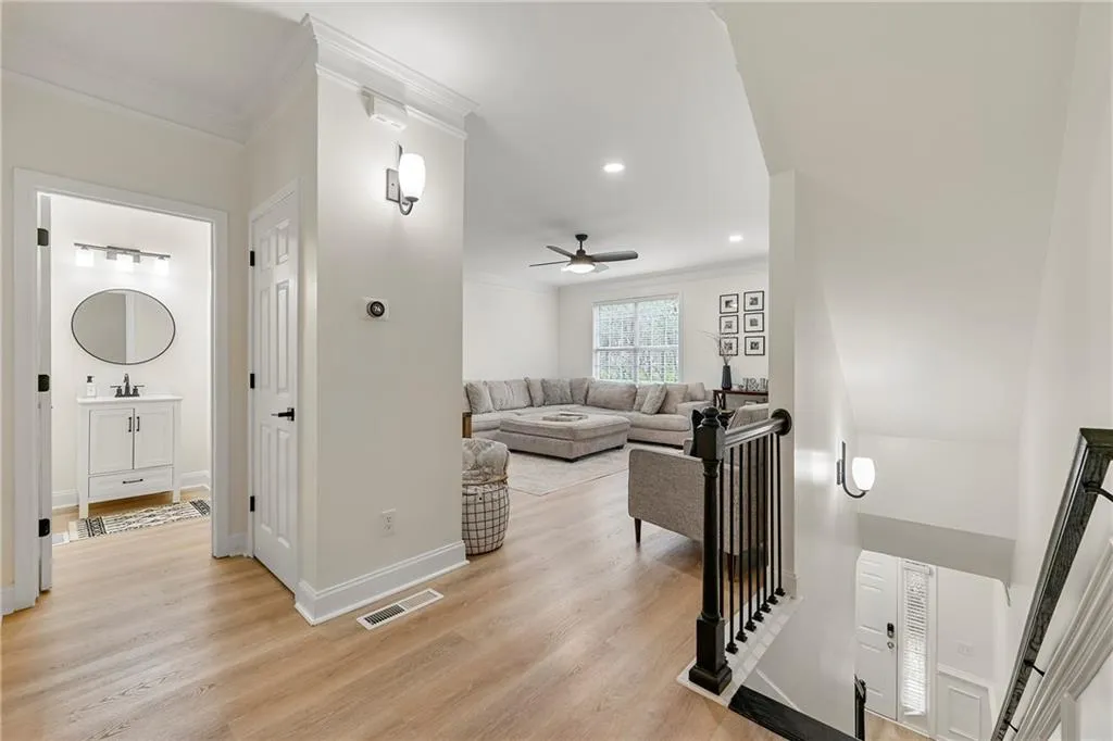 Living room with ceiling fan, crown molding, and light wood-type flooring