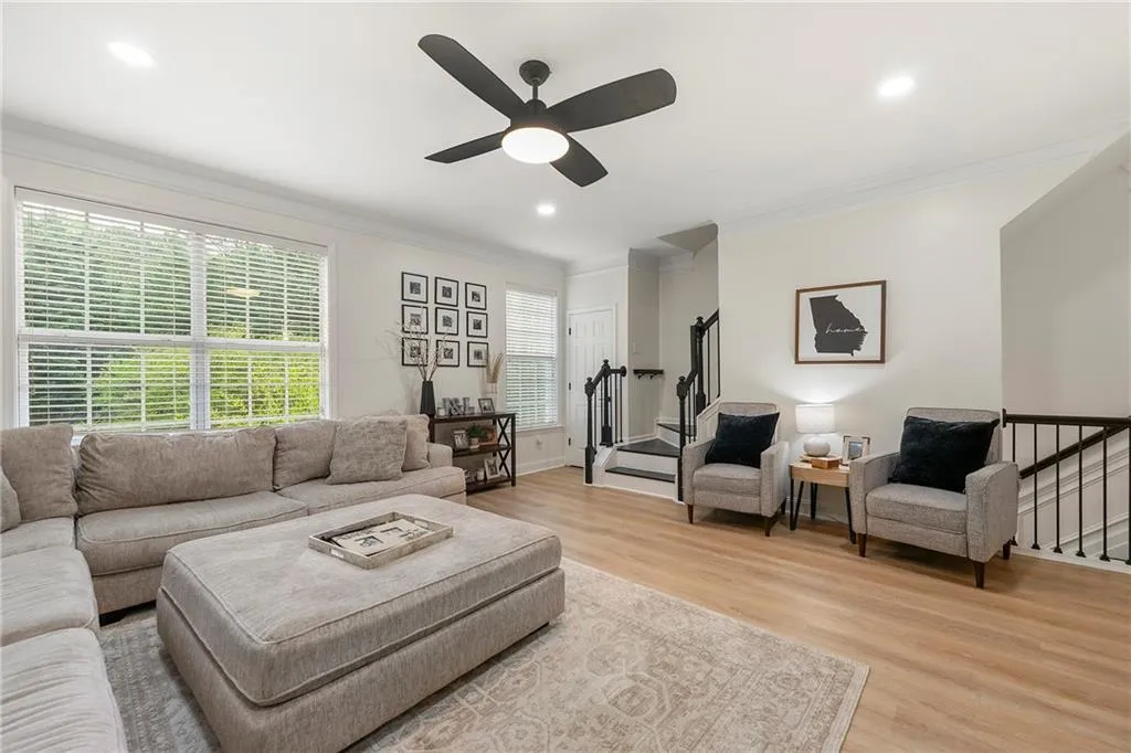 Living room with ceiling fan, light hardwood / wood-style floors, and ornamental molding