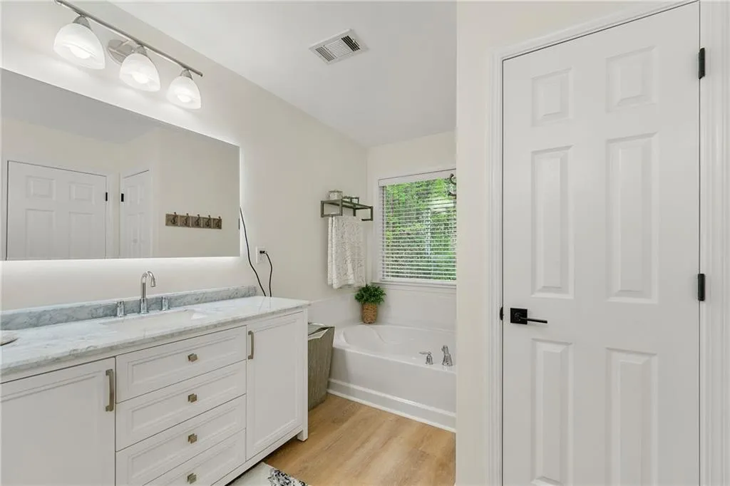 Bathroom featuring wood-type flooring, vanity, and a bath