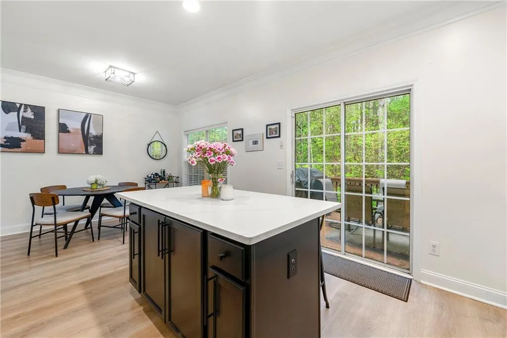 Kitchen featuring light stone counters, crown molding, light wood-type flooring, and a kitchen island
