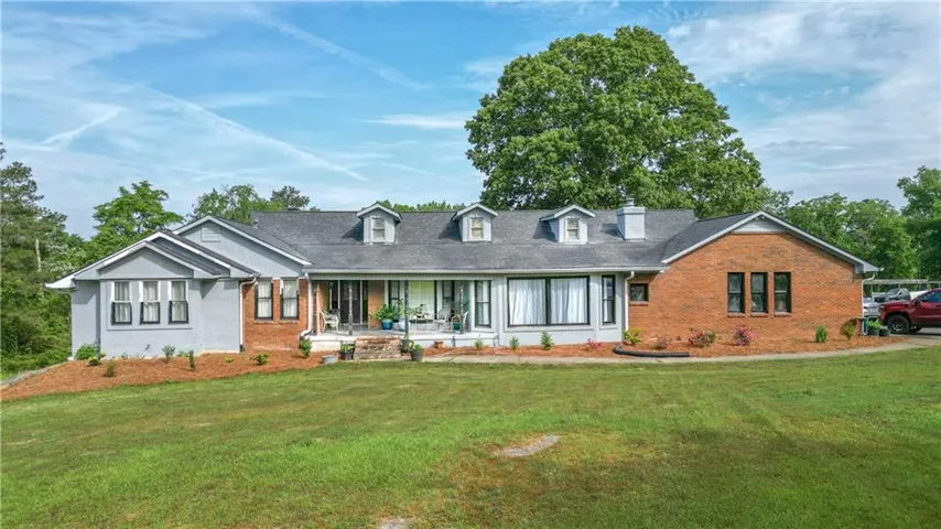 Cape cod home with a porch, brick siding, and a front yard