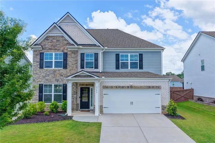 Two-story residence featuring stone and siding exterior, an attached two-car garage, and a covered front entry