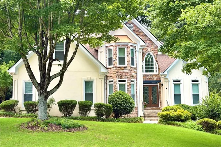 Stucco and stone exterior with a prominent bay window, arched window detailing, and a double-door entry