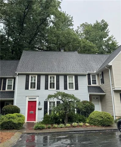 Light blue siding exterior with a bright red front door, featuring black shutters on multiple windows