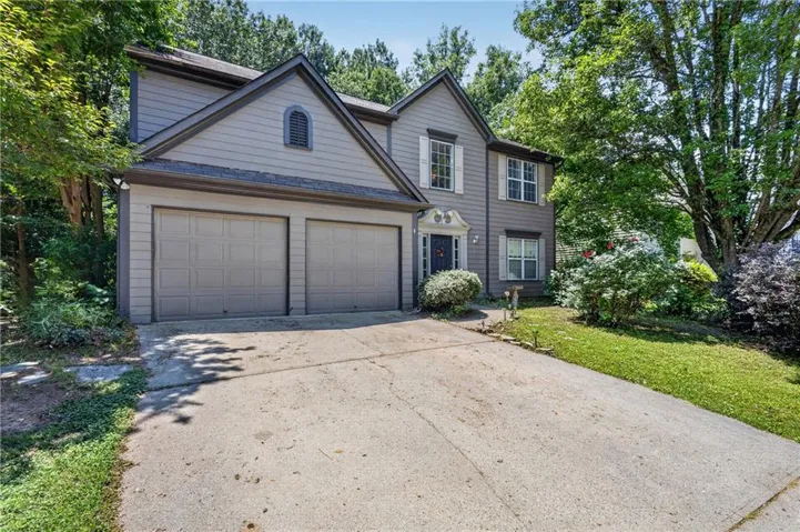 Two-story residence featuring grey siding with white window shutters, a prominent front entry, a two-car garage, and a concrete driveway