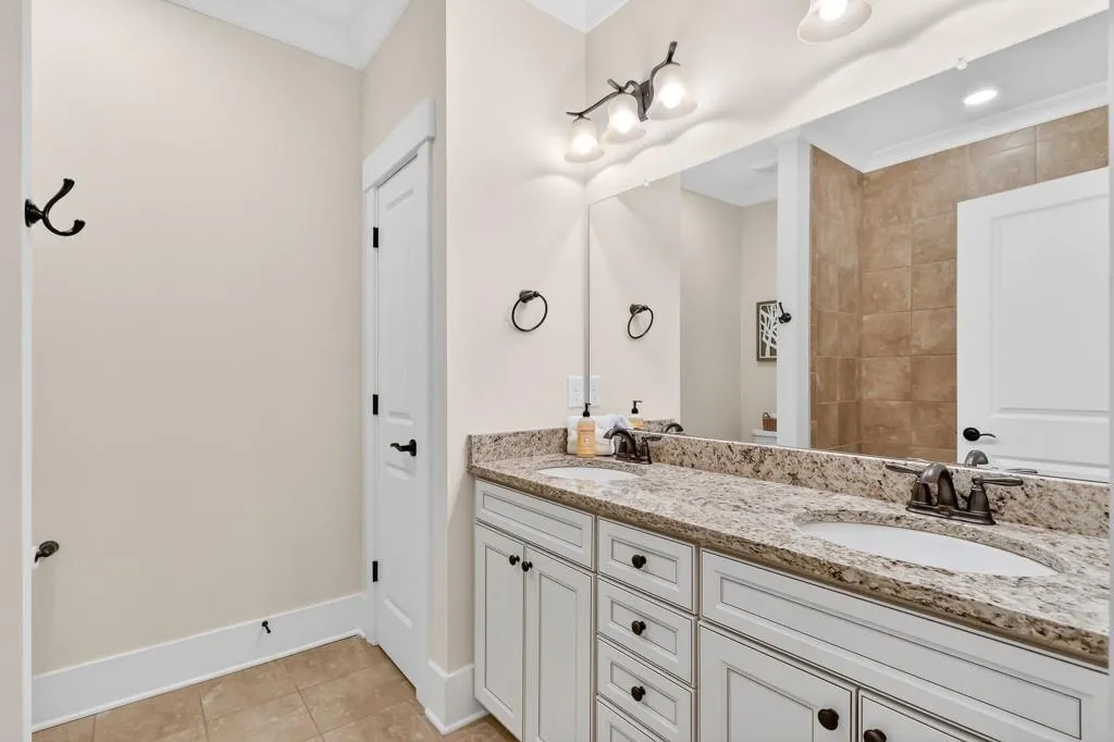 Bathroom with crown molding, double vanity, and light tile patterned floors
