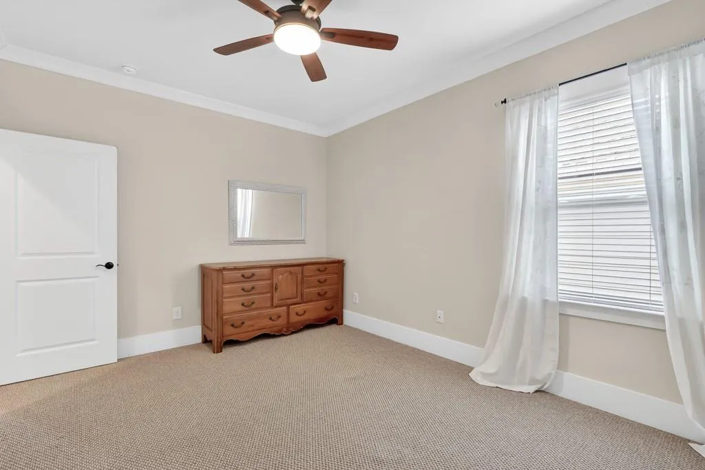 Carpeted bedroom with crown molding and ceiling fan