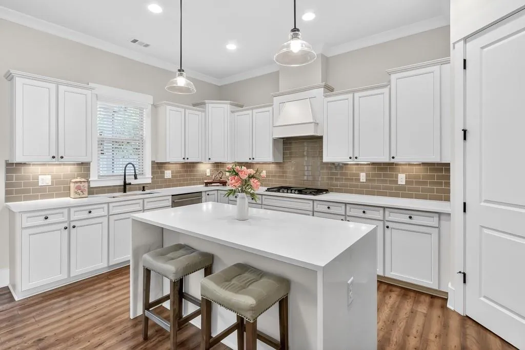 Kitchen with a kitchen breakfast bar, decorative light fixtures, white cabinets, light stone countertops, and crown molding