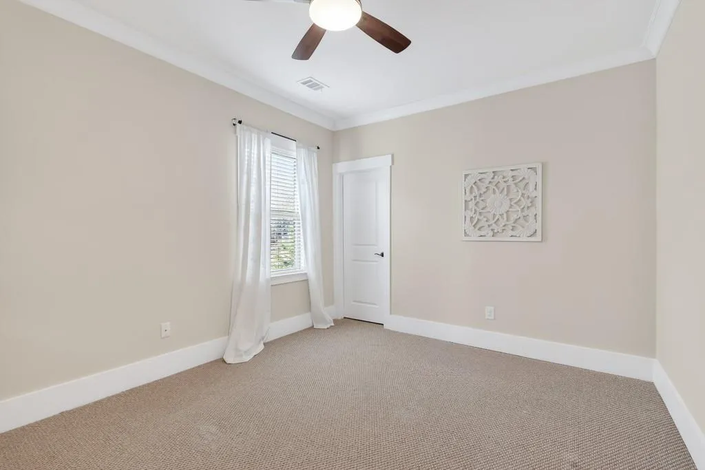 Spare room with ornamental molding, carpet, and a ceiling fan