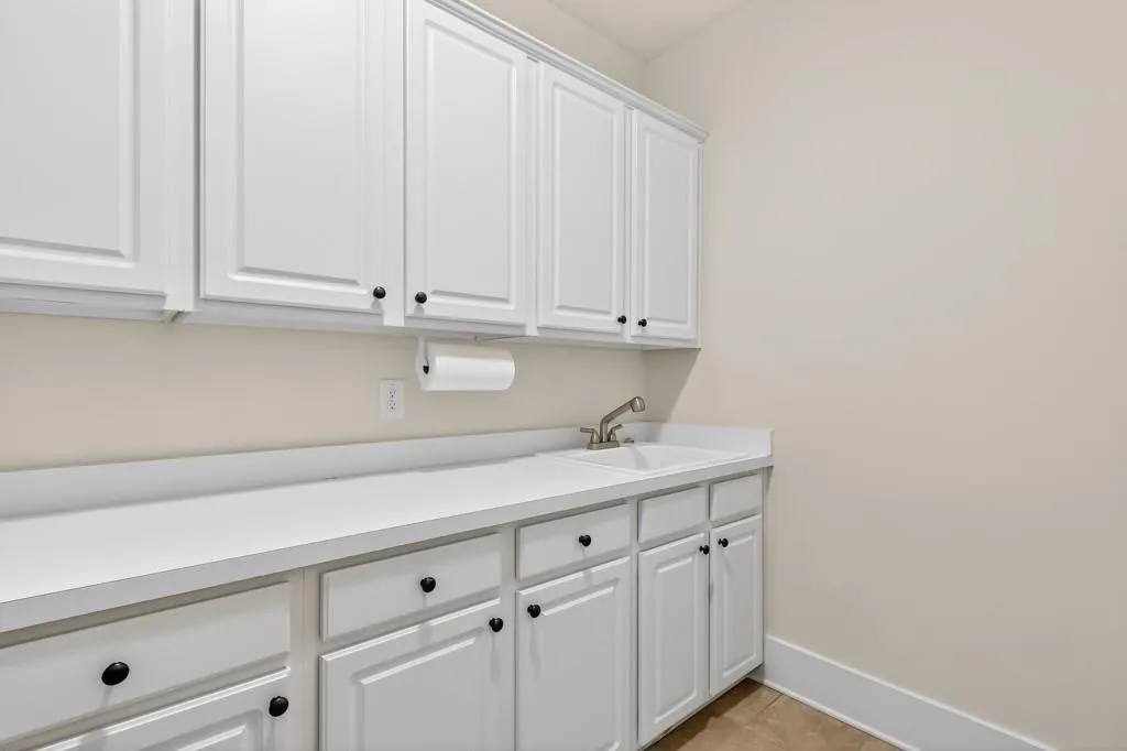 Laundry area with a sink and light tile patterned flooring