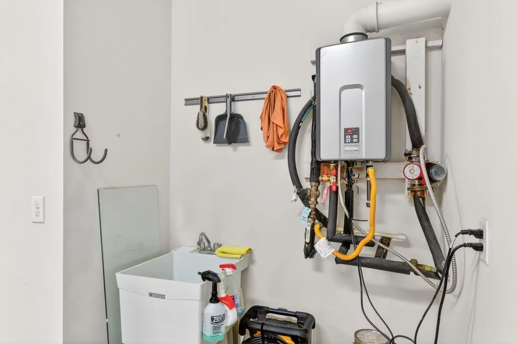 Utility room featuring tankless water heater and a sink
