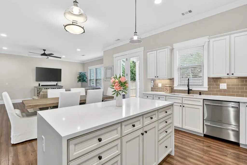 Kitchen with white cabinets, stainless steel dishwasher, pendant lighting, tasteful backsplash, and open floor plan