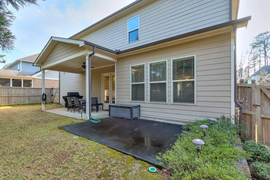 Rear view of property with a fenced backyard, a ceiling fan, and a patio area