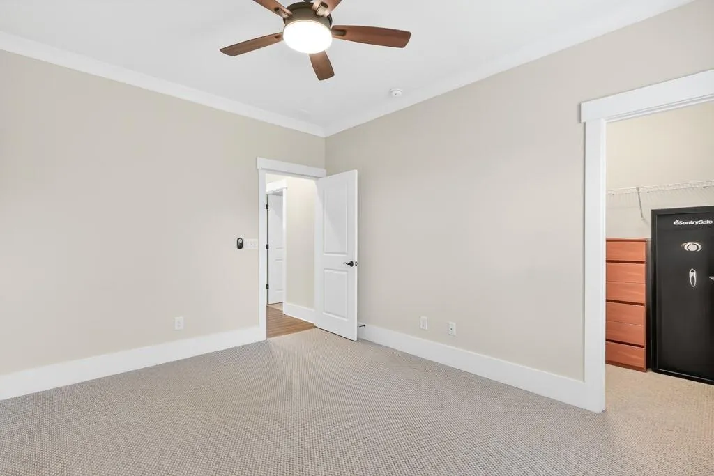 Unfurnished bedroom with carpet floors, crown molding, ceiling fan, and a walk in closet