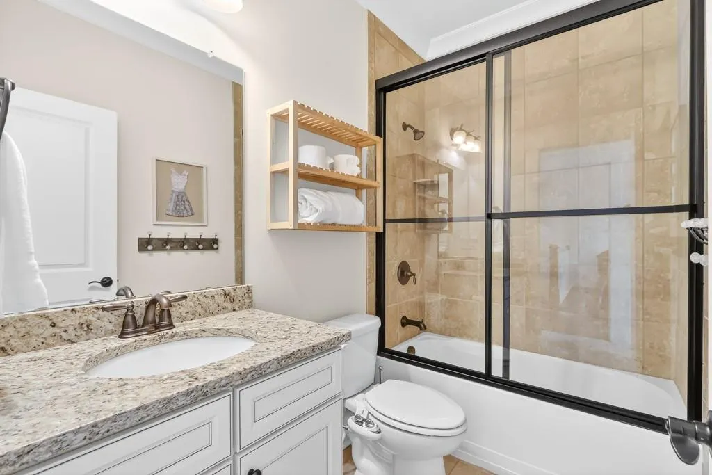 Bathroom featuring bath / shower combo with glass door and vanity