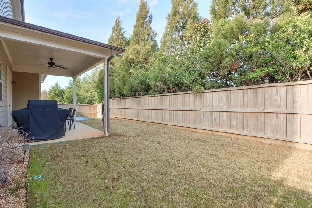 Fenced backyard featuring ceiling fan and a patio area