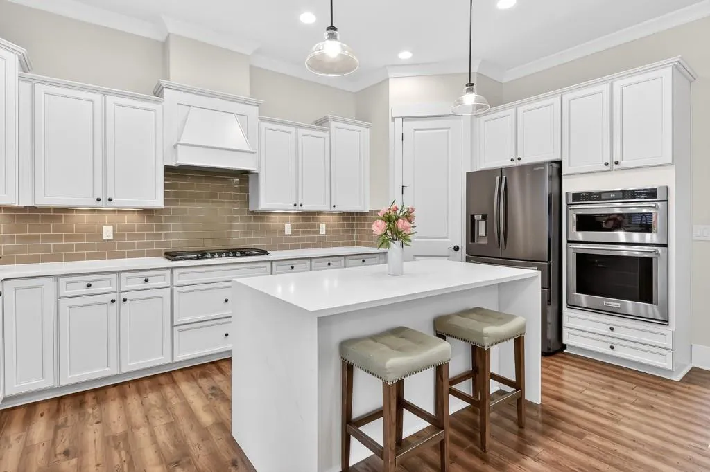 Kitchen featuring a breakfast bar area, stainless steel appliances, a kitchen island, ornamental molding, and hanging light fixtures