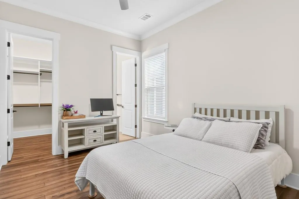 Bedroom with ornamental molding, light wood finished floors, a walk in closet, and a ceiling fan