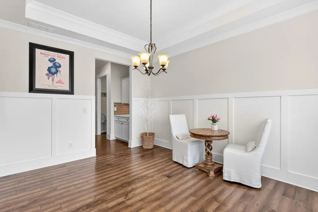 Unfurnished room with a decorative wall, a wainscoted wall, a chandelier, dark wood finished floors, and a raised ceiling