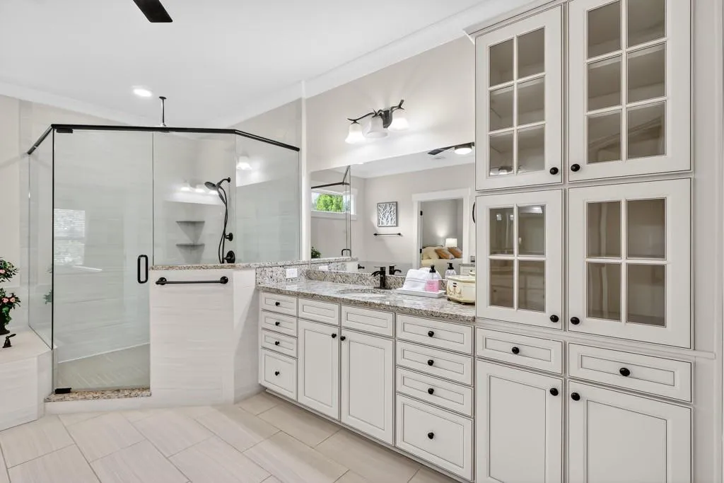 Bathroom featuring vanity, ceiling fan, a stall shower, and crown molding