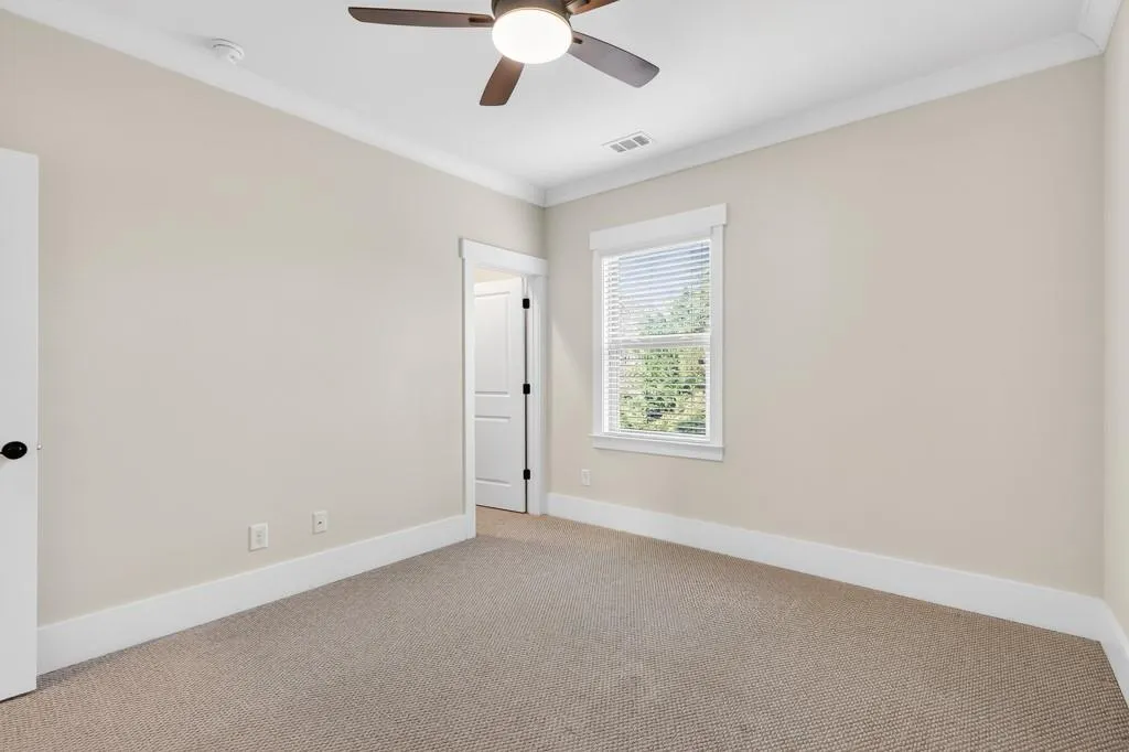 Carpeted spare room featuring ornamental molding and a ceiling fan