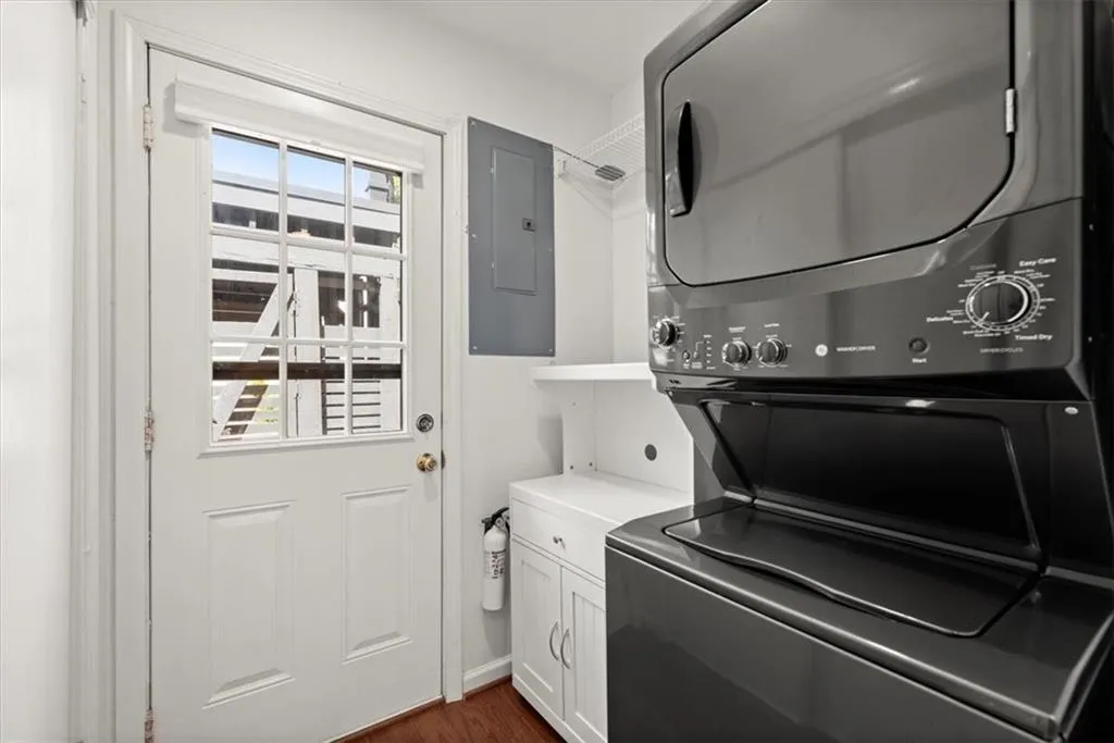 Laundry/mud room with stacked washer / dryer, dark hardwood / wood,cabinets, and pantry