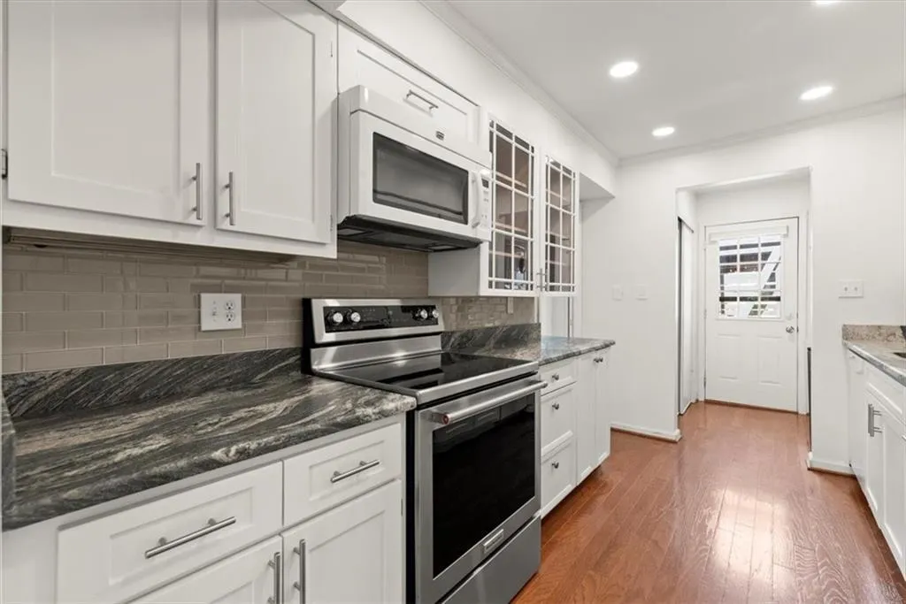 Kitchen featuring white cabinetry, dark hardwood and stainless steel range with electric cooktop