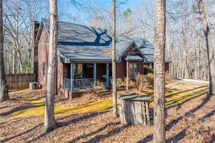 View of front of property with brick siding, a porch, a metal roof, and a chimney