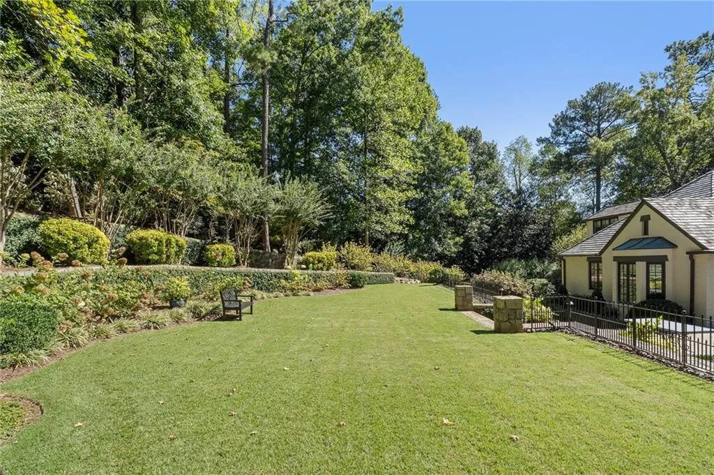 Lawn stretches across backyard with gardens and walking trails all around itl