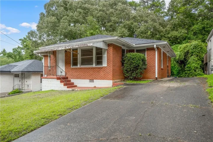 Brick exterior with a covered entry, exterior lighting, and a paved driveway