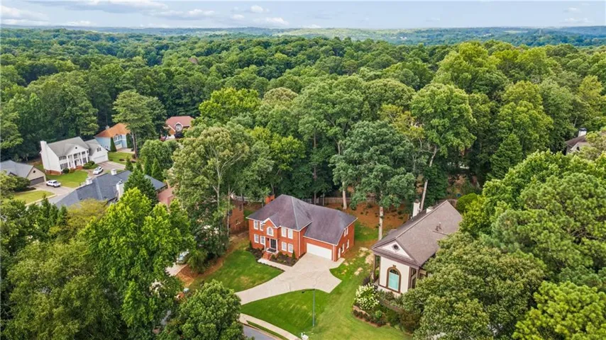 Brick exterior residence with an attached garage, paver driveway, and mature landscaping, set within a tree-lined neighborhood