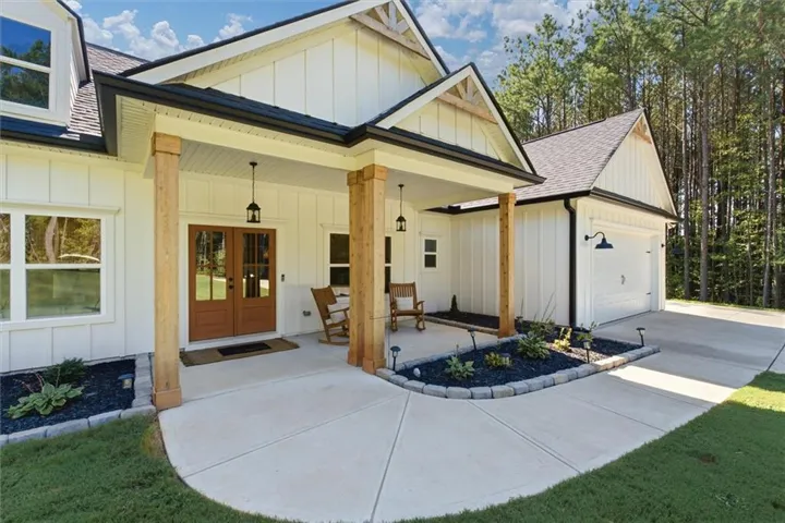 Board and batten siding, substantial wood columns, double entry doors with glass panels, covered porch, and a two-car garage