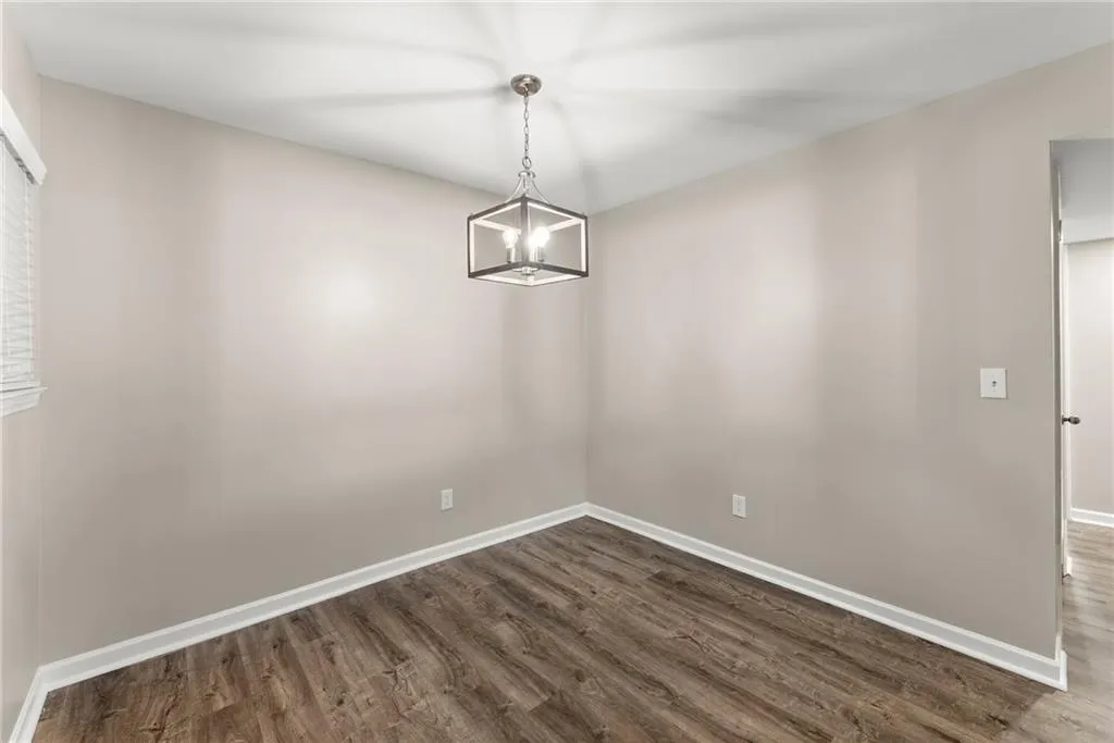 Unfurnished dining area featuring hardwood / wood-style flooring and an inviting chandelier
