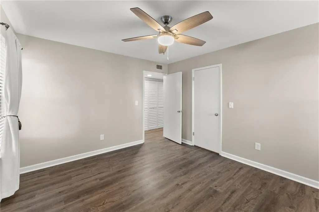 Unfurnished bedroom with ceiling fan and dark hardwood / wood-style floors