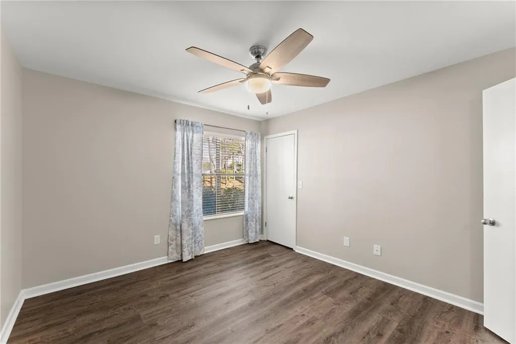 Empty room featuring ceiling fan and dark hardwood / wood-style floors