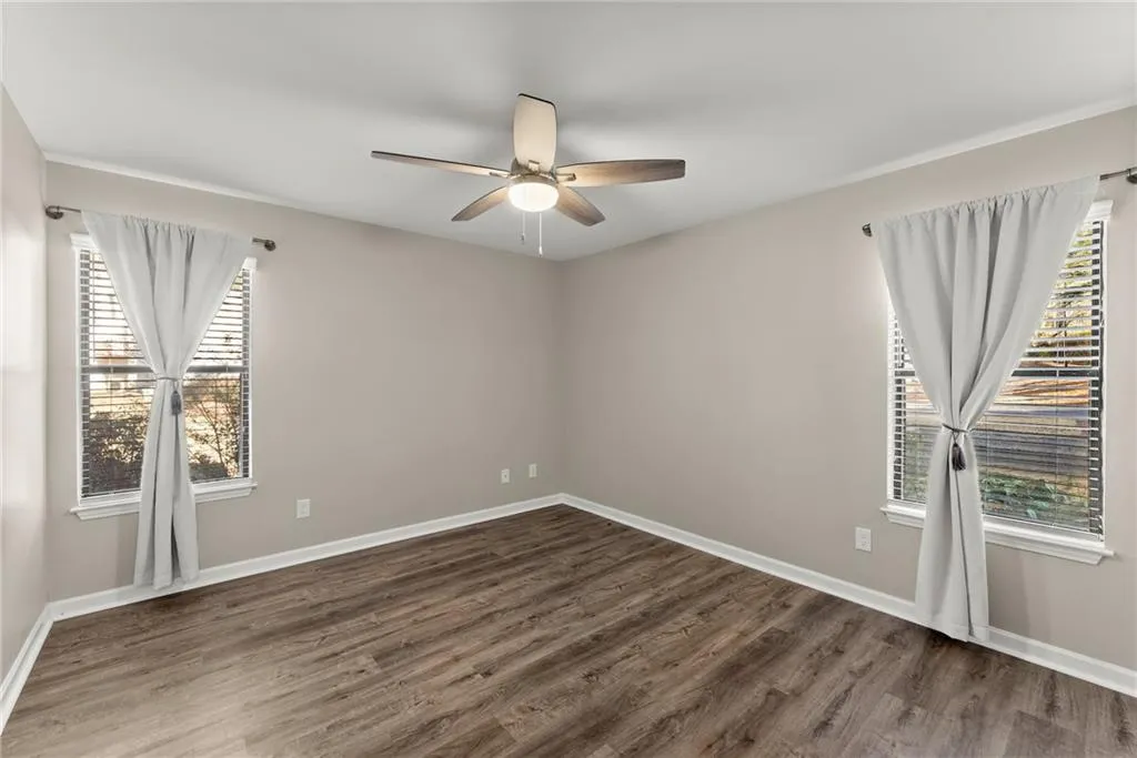 Unfurnished room with ceiling fan, plenty of natural light, and dark wood-type flooring