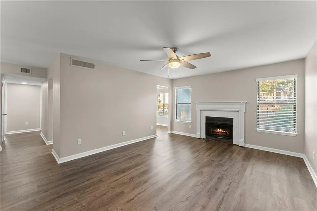Unfurnished living room with ceiling fan, dark hardwood / wood-style flooring, and a wealth of natural light