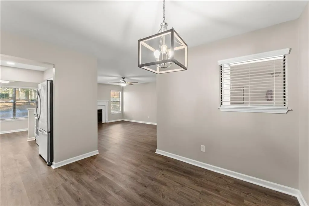 Unfurnished dining area featuring dark wood-type flooring and ceiling fan with notable chandelier