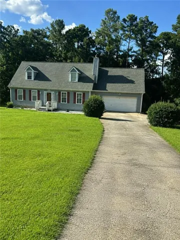 Charming Colonial-style residence featuring a brick exterior, two-story design with dormers, attached two-car garage, and a circular driveway